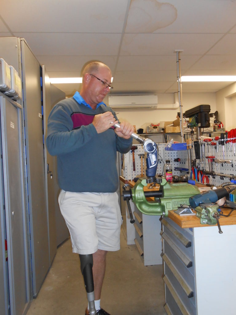 Steve, aged 56, in his workshop. His prosthetic leg is visible under his shorts.