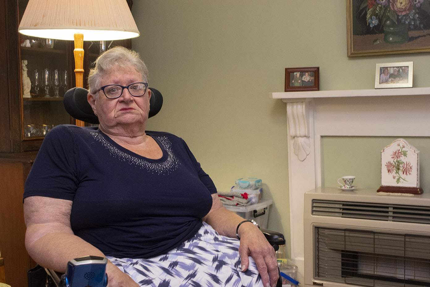 Lyn Bates, 74, sits in her motorised wheelchair in her living room.
