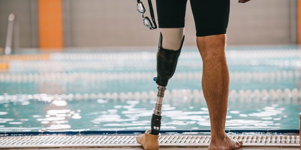 A cropped photo of a swimmer's legs at the poolside. His left leg is a prosthetic.