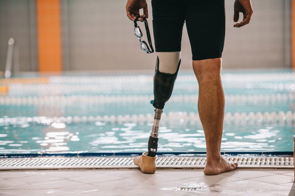 A cropped photo of a swimmer's legs at the poolside. His left leg is a prosthetic.